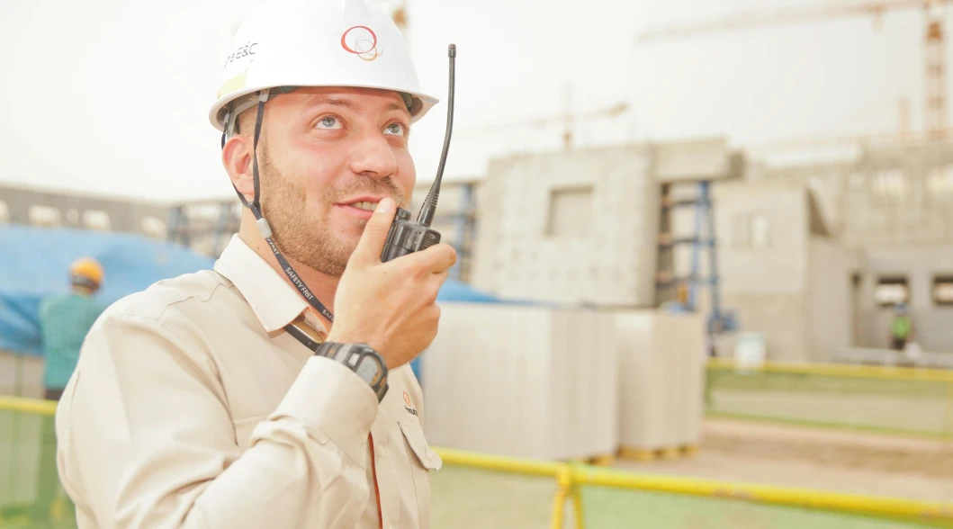 contractor wearing white hard hat holding 2-way radio contractor wearing white hard hat holding 2-way radio