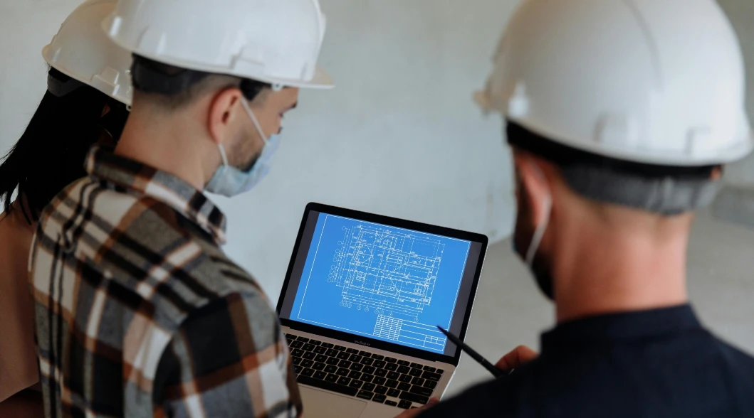 three engineers with hard hats looking at laptop three engineers with hard hats looking at laptop
