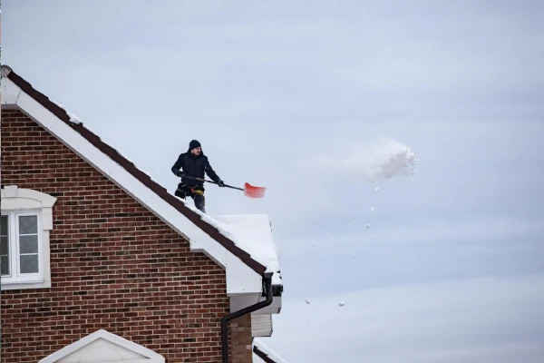 man shovelling snow off a roof man shovelling snow off a roof
